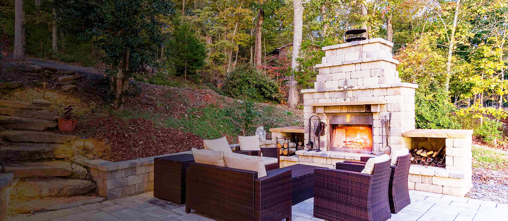 A backyard patio features a fireplace and casual furnishings.