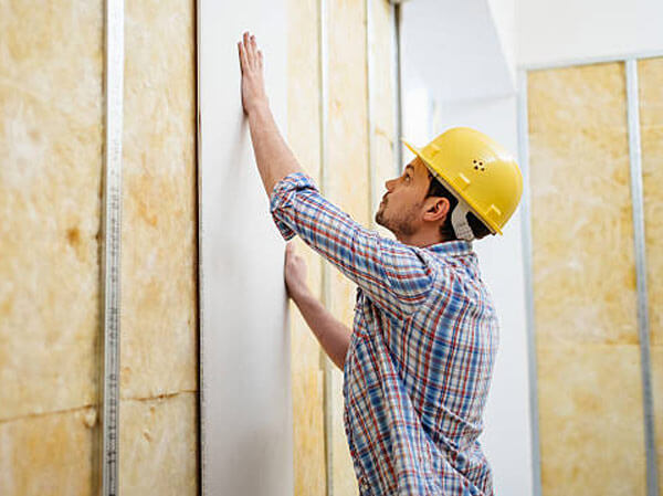 Construction worker on construction site building up a drywall.